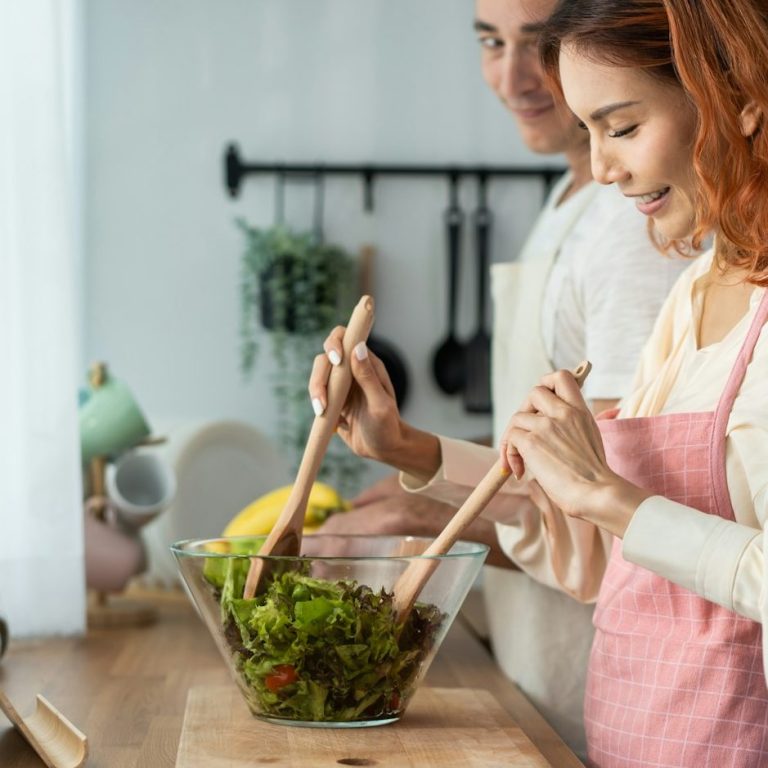 Mann und Frau machen in der Küche einen grünen Salat
